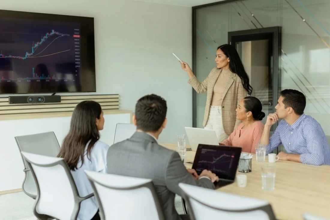 A consultant presenting a performance chart to colleagues in a boardroom